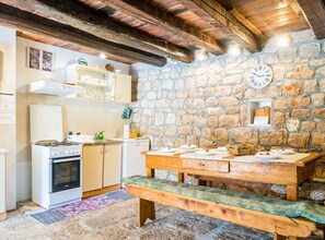 Une cuisine rustique avec des murs en pierre, un plafond en bois et un banc en bois.
