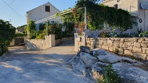 Ein Wohngebiet mit einem befestigten Weg, der zu einem Haus mit Steinmauer und Metallgitter führt.