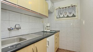 Een kleine keuken met een spoelbak, een koffiezetapparaat en een raam met een kantelaar.