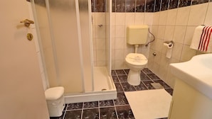 Une salle de bain avec douche, toilettes et lavabo.