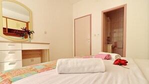 Une chambre d’hôtel avec un lit, une commode, un miroir et une salle de bain visible à travers une porte ouverte.