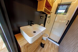 A compact bathroom with a white sink, wooden vanity, and a toilet. - Prague Bay Houseboats (Prague)