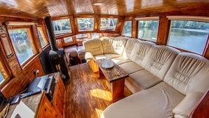 A cabin with a wooden interior, a sofa, a table, and a fireplace. - Prague Bay Houseboats (Prague)