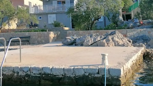 A coastal property with a swimming pool, stone walls, and a view of the sea.