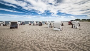 A beach with rows of white beach chairs and sun loungers, some with umbrellas. - traumHaff®Romance of the boatswains with fireplace, private NORDICSPA, fireplace (Rieth am See)