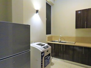 Una cocina compacta con refrigerador, lavadora y lavamanos.