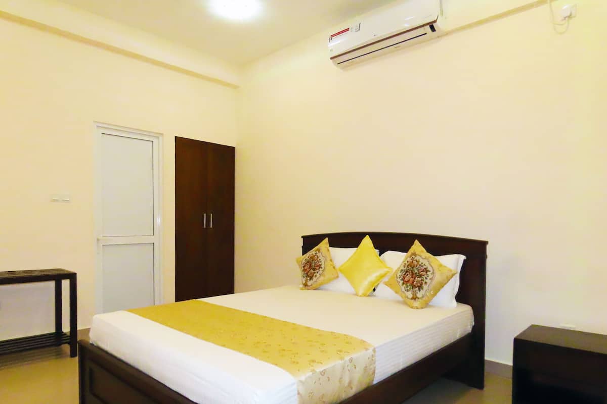 A neatly made bed with a white and yellow bedspread, a wooden headboard, and decorative pillows.