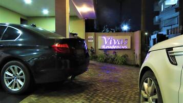 A gated entrance with a sign for 'Vivas Residencies' and two cars parked in front.
