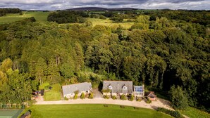 A large estate with multiple buildings, surrounded by dense forest and open fields.
