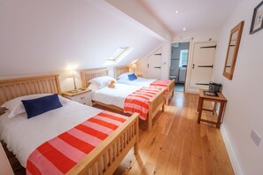 Un dormitorio con tres camas de madera, un tragaluz y suelo de madera.