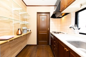 A kitchen with wooden cabinets, a stainless steel sink, and a countertop with various kitchen items. - Shinagawa Wisteria Residence (Tokyo)