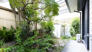 Ein Garten mit einem Kiesweg, einem Baum und einem kleinen Teich.