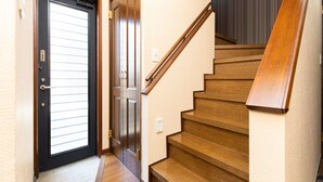 Eine Holztreppe führt zu einer dunklen Tür mit Glasscheibe.