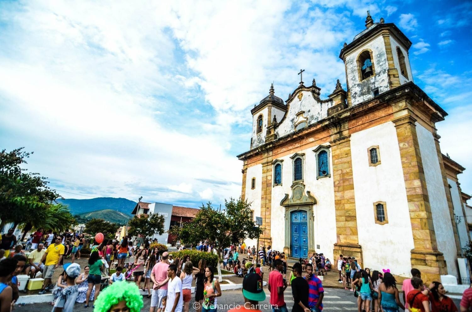 Uma igreja histórica com um campanário e uma multidão de pessoas em frente.