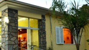 A modern house with a stone facade, a glass door entrance, and a staircase leading to the front door. - Hotel Pousada Cassino (Caete)