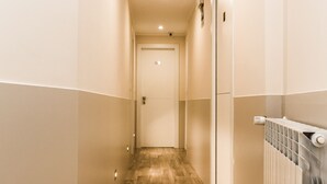 A narrow hallway with wooden flooring, a radiator on the right, and a door at the end. - Domus Porta Angelica (Rome)