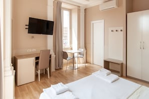A hotel room with a bed, a desk, a chair, a TV, a wardrobe, and a window with curtains. - Domus Porta Angelica (Rome)