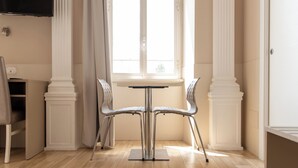 A dining area with a table and two chairs, a window with curtains, and a flat-screen TV mounted on the wall. - Domus Porta Angelica (Rome)