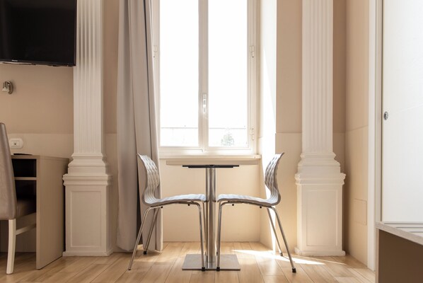 A dining area with a table and two chairs, a window with curtains, and a flat-screen TV mounted on the wall. - Domus Porta Angelica (Rome)