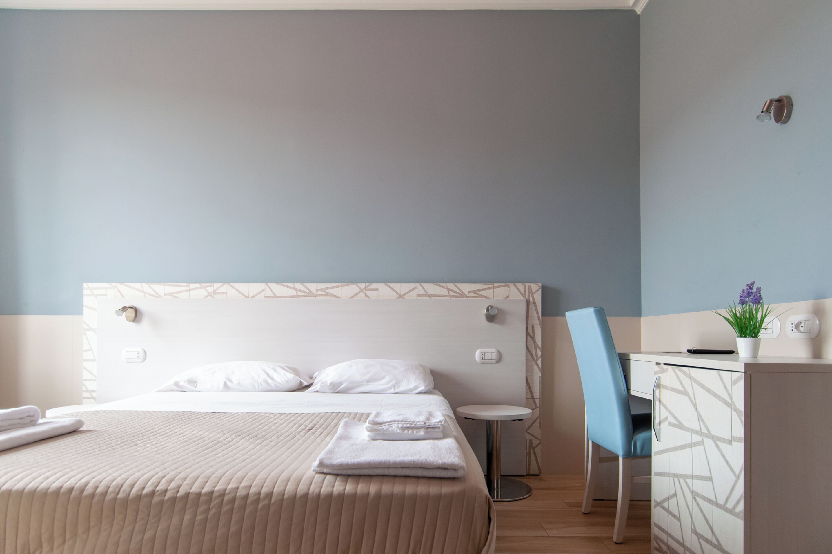 A hotel room with a bed, a desk, and a chair.