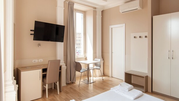 A hotel room with a bed, a desk, a chair, a TV, and a wardrobe. - Domus Porta Angelica (Rome)