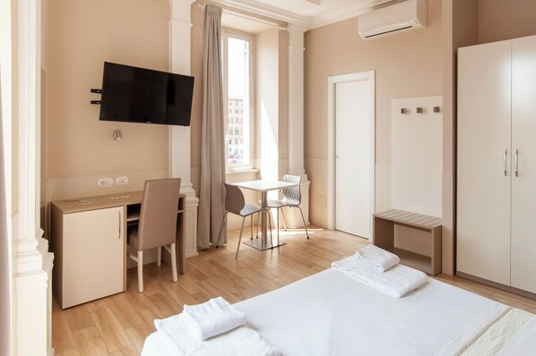 A hotel room with a bed, a desk, a chair, a TV, and a wardrobe. - Domus Porta Angelica (Rome)