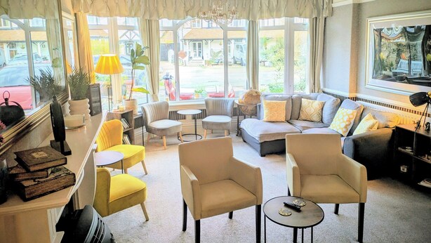 A room with a sofa, armchairs, a small table, and a chandelier. - Sunnycroft Guesthouse (Llandudno)