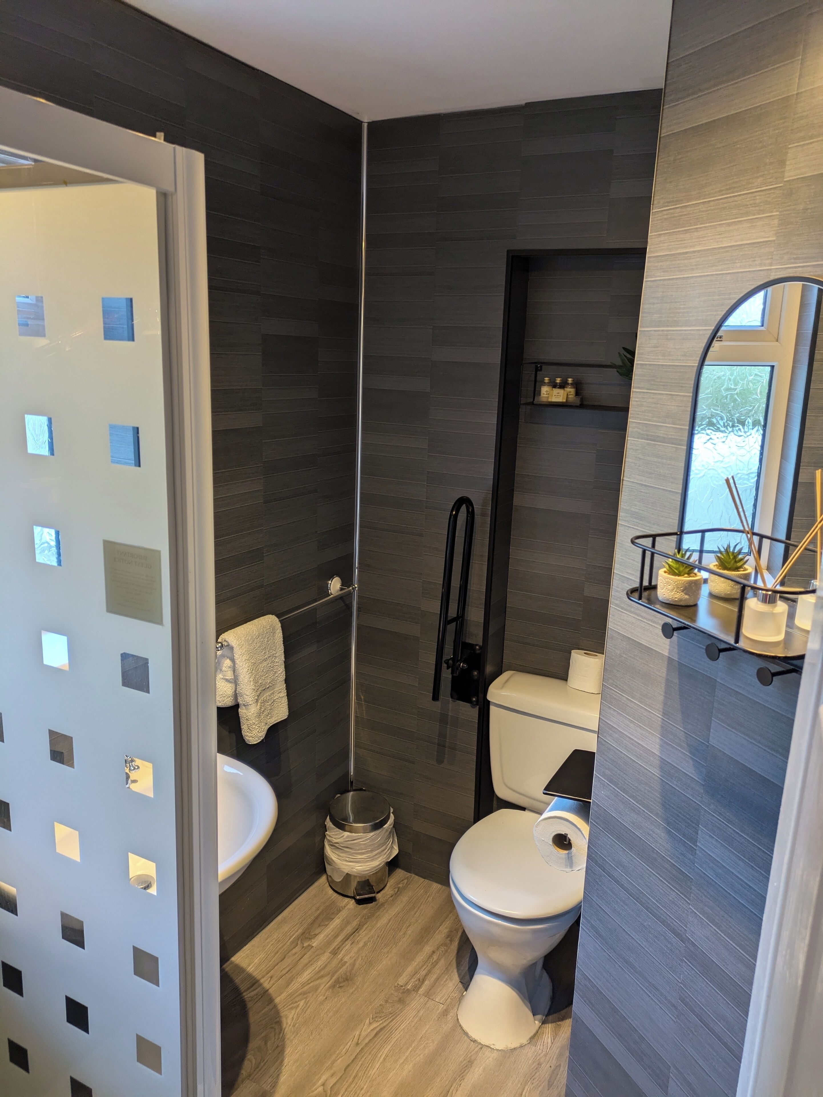 A modern bathroom with a glass shower enclosure, a white sink, and a toilet.