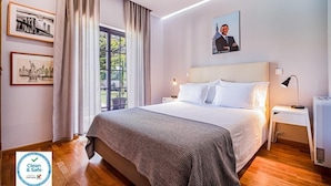 A clean and safe hotel room with a large bed, a nightstand, a lamp, and framed pictures on the wall. - Buganvilia do Meco B&B (Sesimbra)