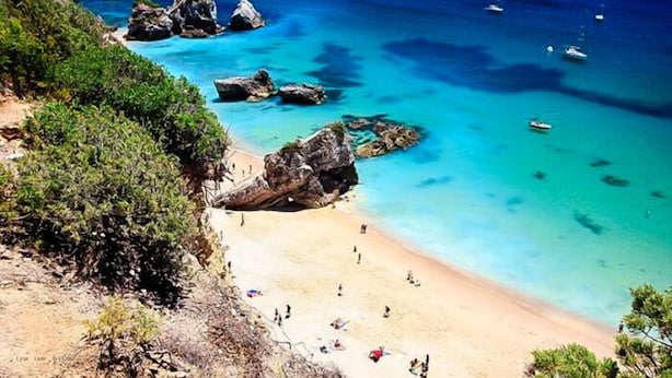 A coastal beach with clear turquoise waters, rocky outcrops, and a few boats. - Buganvilia do Meco B&B (Sesimbra)