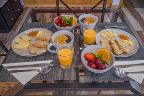 Une table de petit-déjeuner avec des assiettes de toasts, du fromage et des fruits, accompagnées de tasses de café et de jus d ’orange.