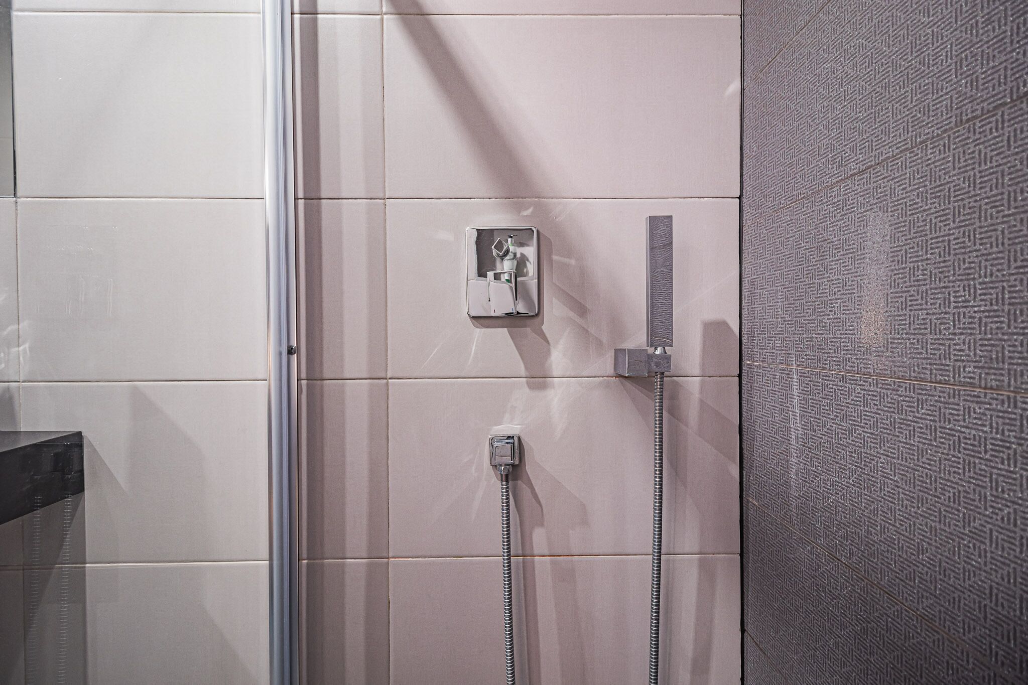 A shower area with a control panel and two showerheads.