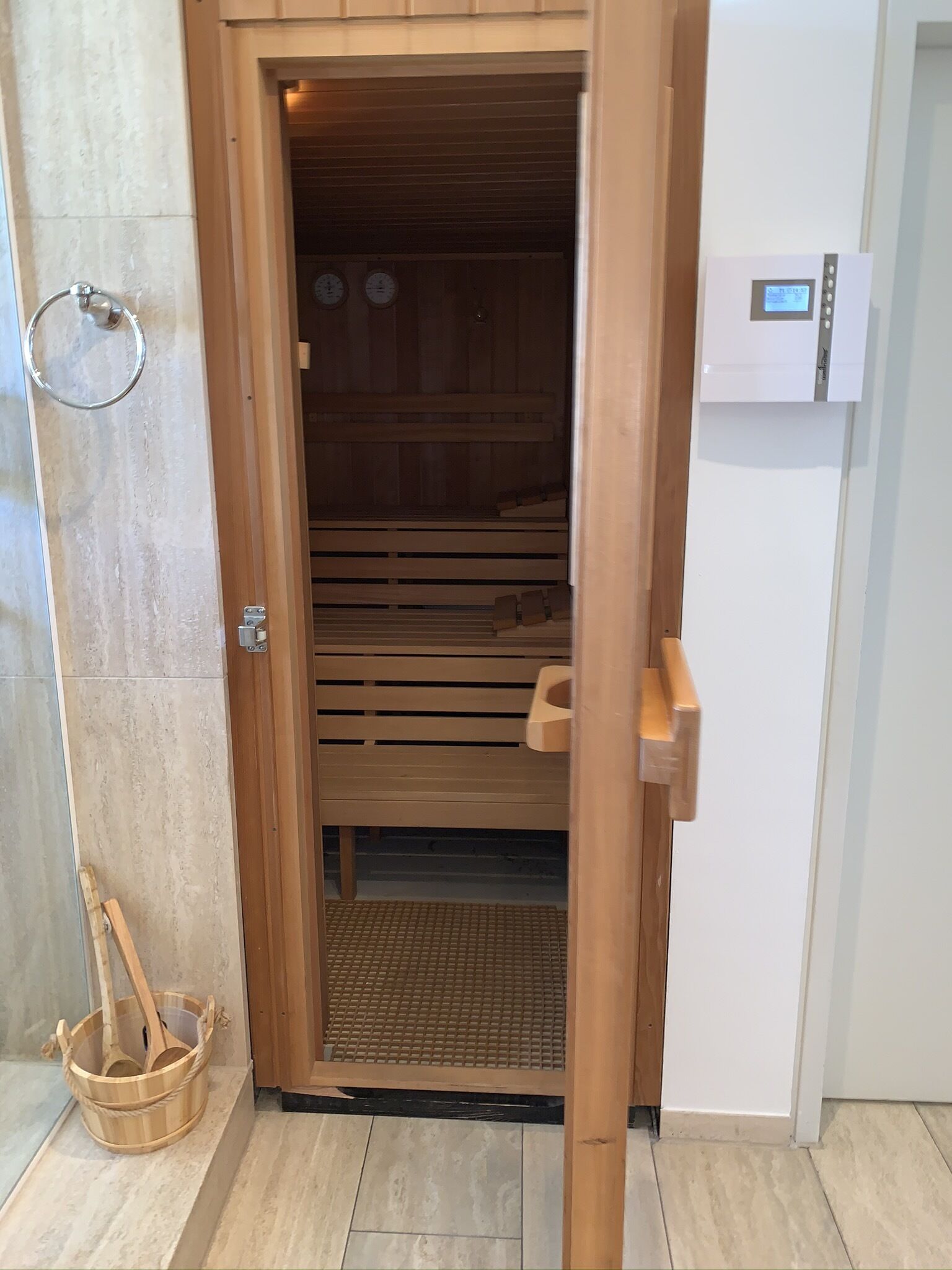 A sauna with a wooden interior, a control panel, and a wooden bench.