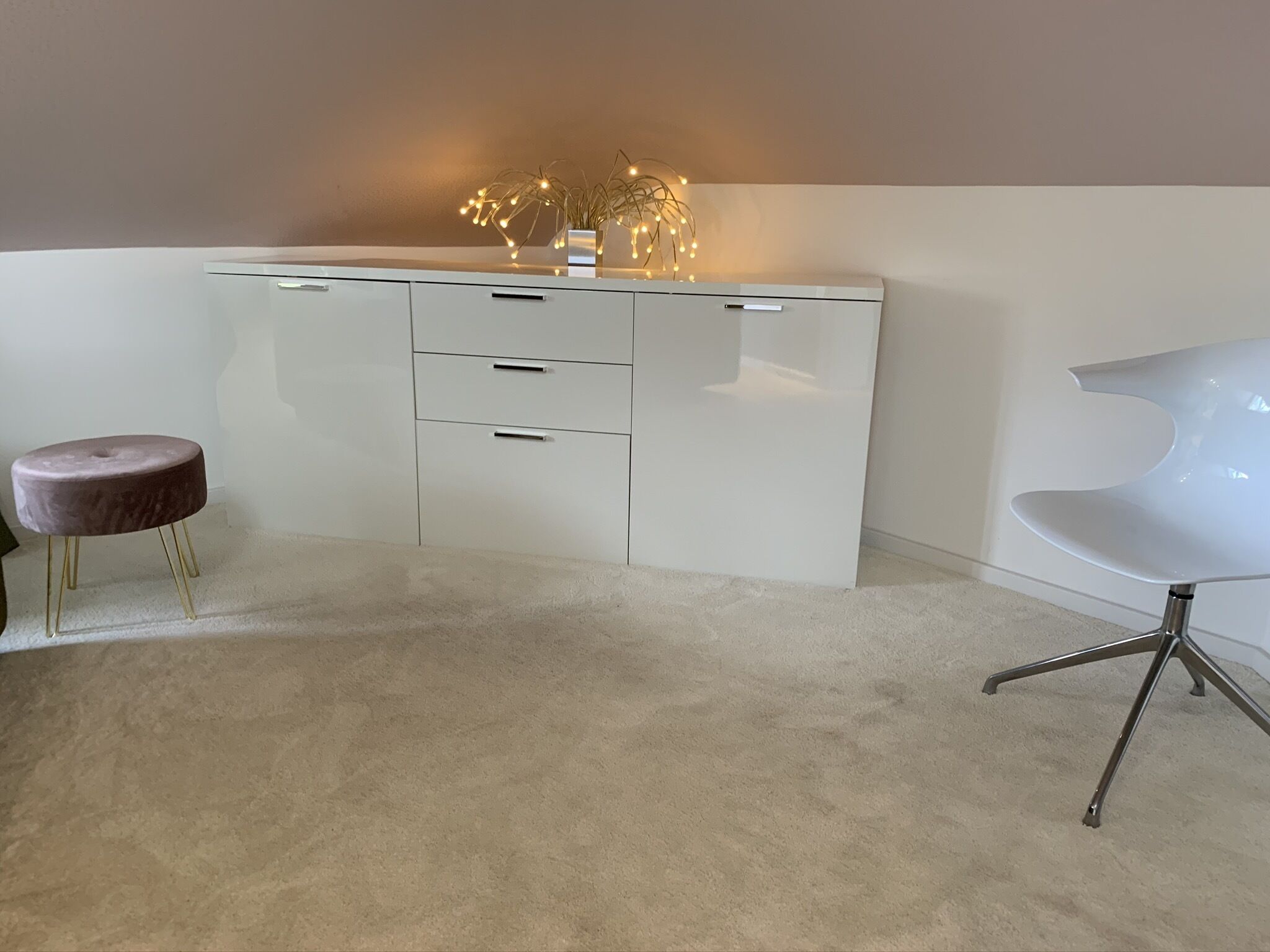Una habitación moderna con un escritorio blanco, un taburete redondo y una silla blanca.