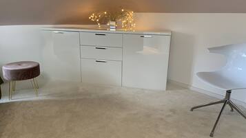 Una habitación moderna con un escritorio blanco, un taburete redondo y una silla blanca.