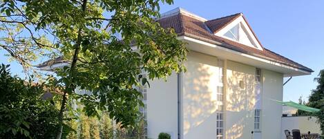 A two-story house with a tiled roof, a visible window, and a door.
