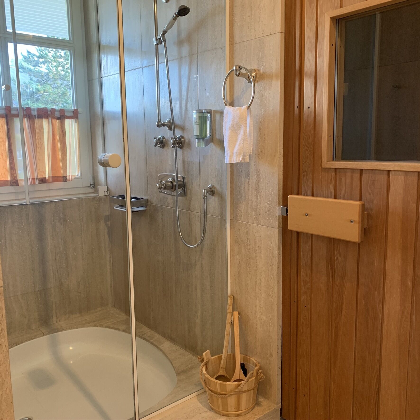 A modern bathroom with a glass-enclosed shower, a bathtub, and a wooden vanity with a mirror.