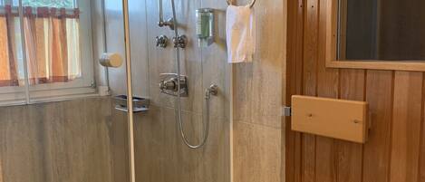 A modern bathroom with a glass-enclosed shower, a bathtub, and a wooden vanity with a mirror.