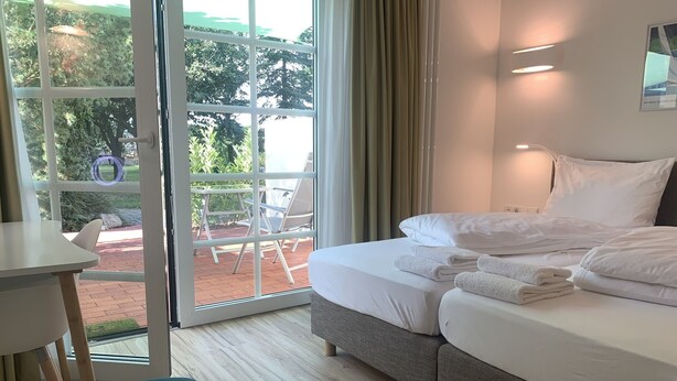 Una camera d'albergo con un letto, un tavolo, una sedia e vista sulla zona esterna.