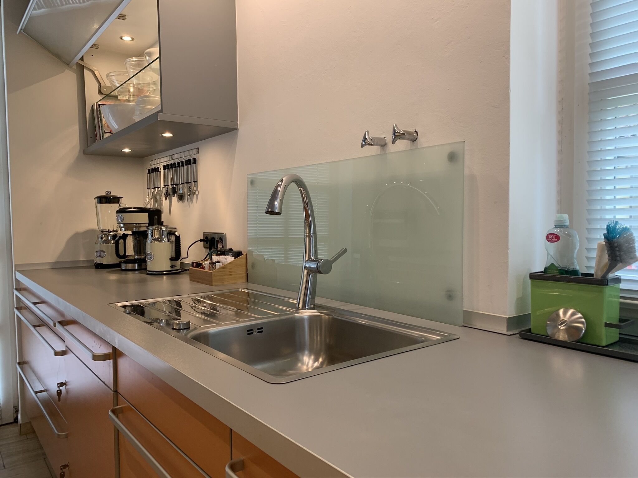 A modern kitchen with a stainless steel sink, a coffee maker, and a set of knives on the wall.