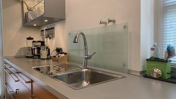 A modern kitchen with a stainless steel sink, a coffee maker, and a set of knives on the wall.
