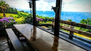 An outdoor seating area with a wooden bench and table, overlooking a scenic landscape with greenery and a view of the ocean. - Maddiola Apart 6, Orio (Orio)