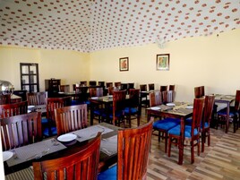 Un comedor con varias mesas y sillas, un techo con diseño y obras de arte enmarcadas en las paredes.
