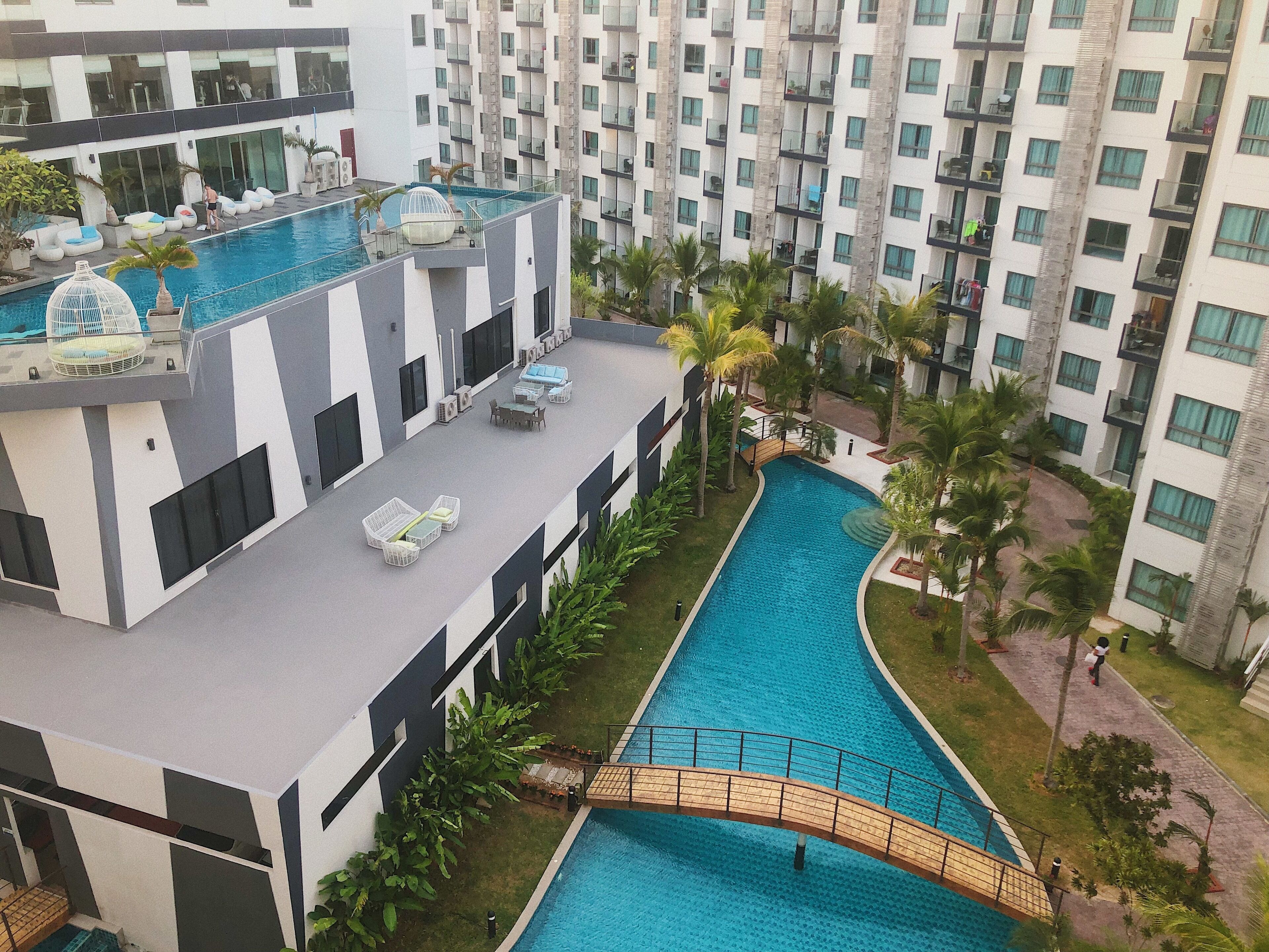 A modern hotel with a rooftop pool, outdoor seating, and a bridge over the pool.