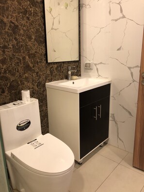 A bathroom with a white toilet, a white sink, and a black cabinet.