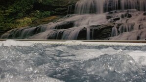 Uma cascata despencando sobre rochas, com um lago de água na base.