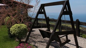 Um baloiço de madeira num jardim com vista para o mar.