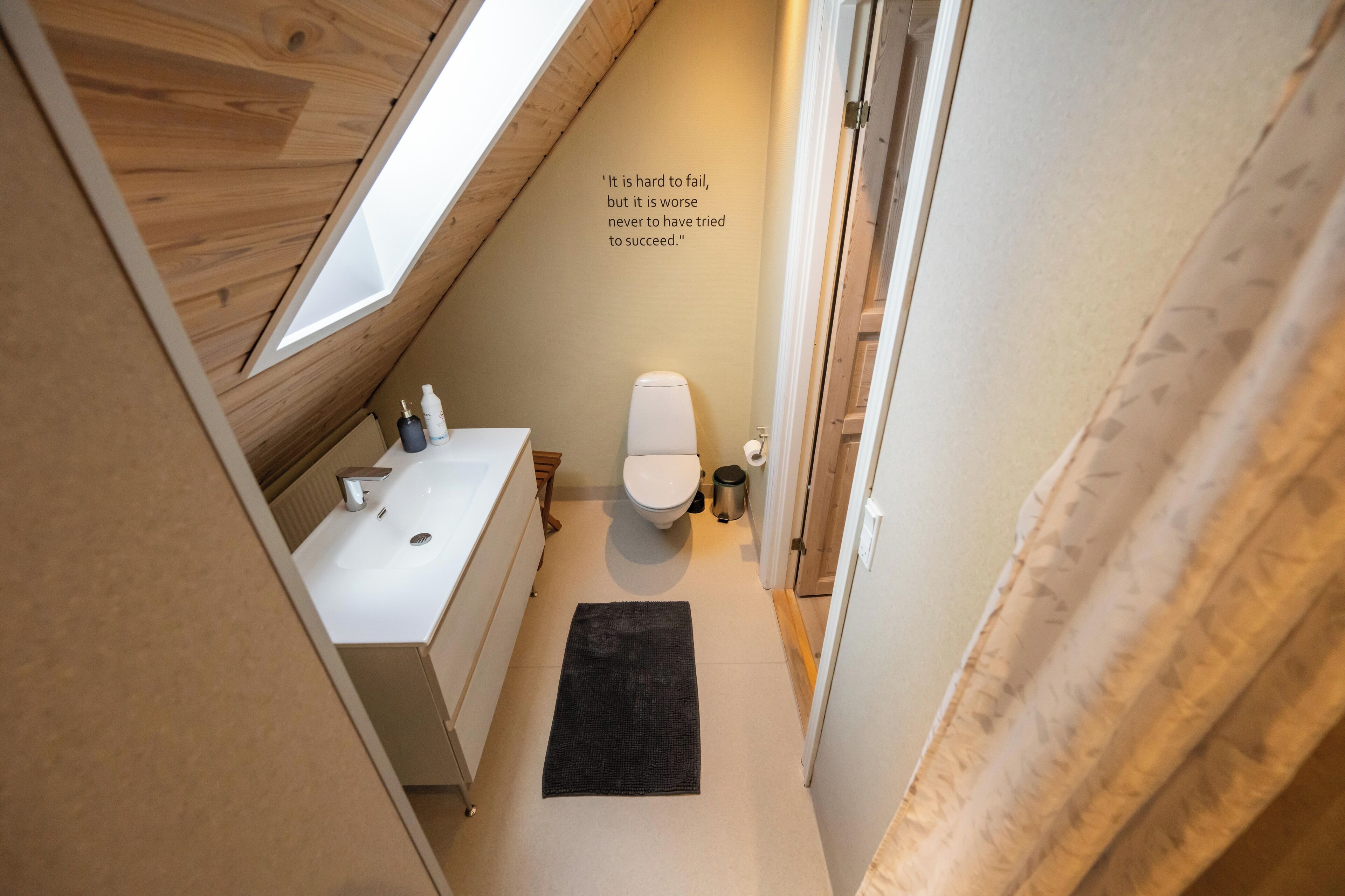 Un baño pequeño y moderno con tragaluz, un lavamanos blanco y un inodoro.