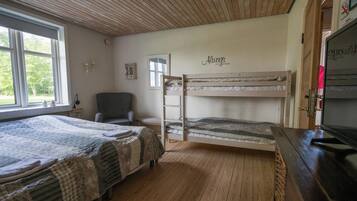 A room with two bunk beds, a chair, a desk, and a television.