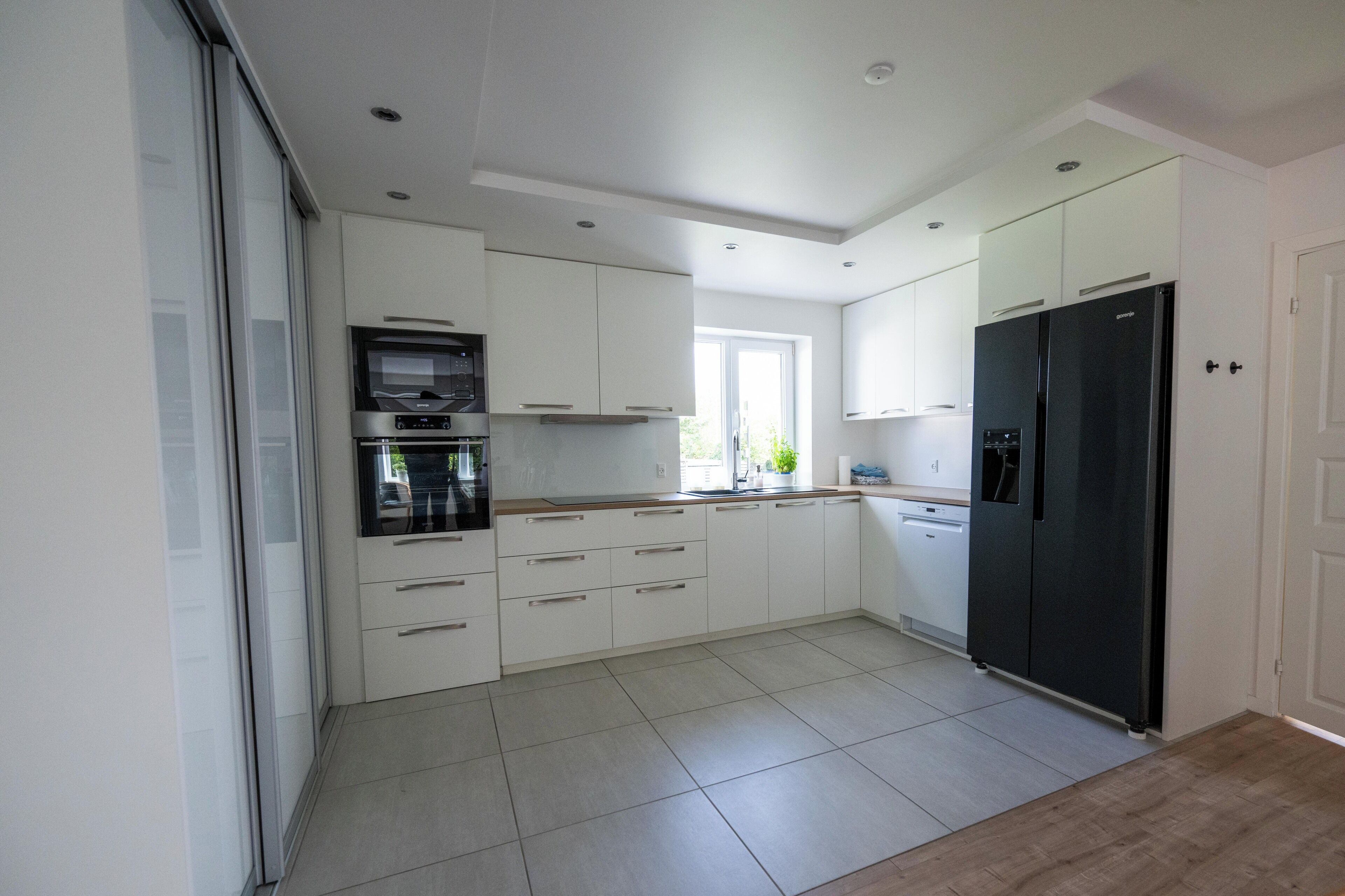 A modern kitchen with white cabinetry, a black refrigerator, and a built-in oven.